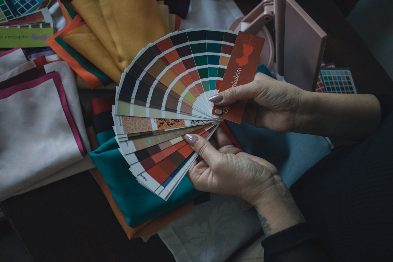 services-01 Hands holding color swatch above fabrics. Ideal for design, fashion, and color theory themes.